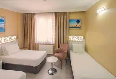 a hotel room with two beds and a chair at GRAND VATAN HOTEL in Istanbul