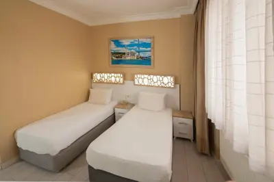 two beds in a small room with a window at GRAND VATAN HOTEL in Istanbul