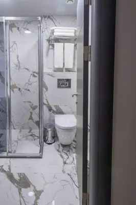 a marble bathroom with a toilet and a mirror at Mardia Hotel in Istanbul