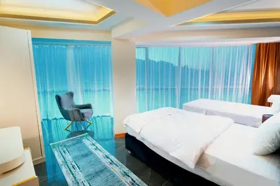 a bedroom with two beds and a chair and a window at Continent Luxury Suites Sakarya in Sakarya