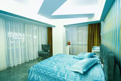 a bedroom with a bed and a chair and windows at Continent Luxury Suites Sakarya in Sakarya
