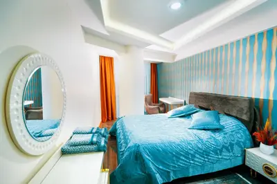 a bedroom with a blue bed and a mirror at Continent Luxury Suites Sakarya in Sakarya