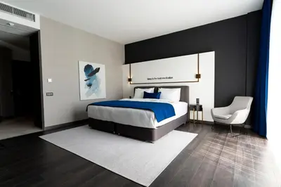 a bedroom with a large bed and a white chair at Hotel Bonvie in Sakarya
