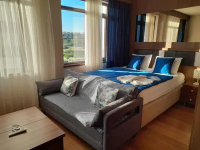 a bedroom with a bed and a couch and a window at Doğan Palas Suites in Istanbul