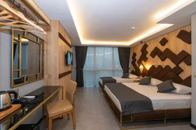 a hotel room with two beds and a desk at Fly And Stay Airport Hotel in Istanbul