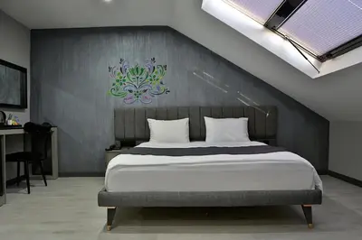 a bedroom with a large bed with a painting on the wall at Fly And Stay Airport Hotel in Istanbul