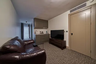 a living room with a leather couch and a kitchen at Selini Hotel İstanbul Airport in Istanbul