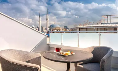 a table and chairs on a balcony with a bowl of fruit at Hotel Bossuite Business in Istanbul
