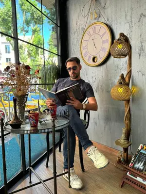a man sitting at a table reading a book at Valeria House in Istanbul