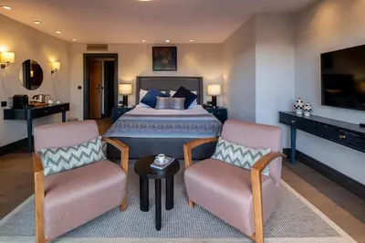a bedroom with a bed and two chairs and a television at Root Hotel Karaköy Bosphorus in Istanbul