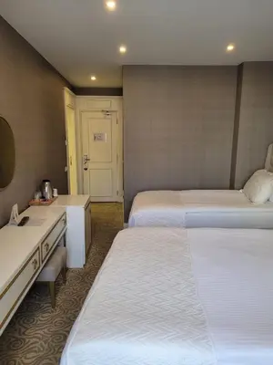 a hotel room with two beds and a desk at Mr BEYAZ HOTEL in Istanbul