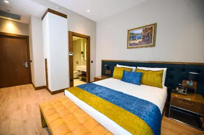 a bedroom with a large bed with blue and yellow pillows at CHER HOTEL & SPA Taksim in Istanbul