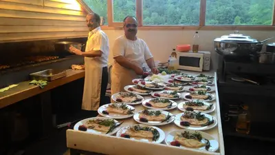two men standing in a kitchen with plates of food at Zumrut Bahce in Gokcedere