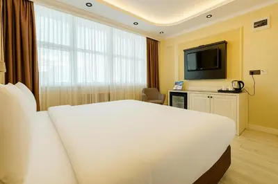 a hotel room with a white bed and a television at FRT AİRPORT OTEL in Arnavutköy