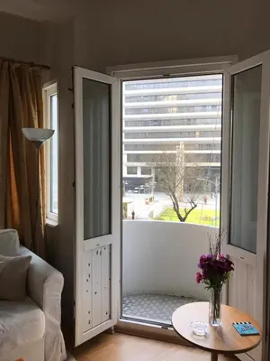 a living room with a large window with a vase of flowers at Cozy Apartment Next to Taksim Square in Istanbul