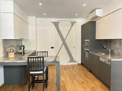 a kitchen with white cabinets and a table with a chair at X Flats Vilhelm in Istanbul