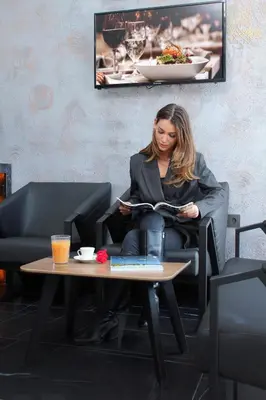 a woman sitting in a chair reading a book at Melanj Airport Hotel in Arnavutköy