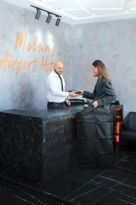 a man and woman shaking hands at a counter at Melanj Airport Hotel in Arnavutköy