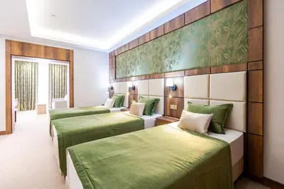 three beds in a room with green sheets at Mardy Suit Hotel in Istanbul
