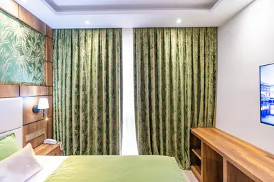 a bedroom with a green bed and curtains at Mardy Suit Hotel in Istanbul