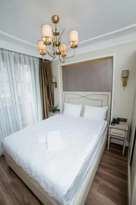 a bedroom with a large white bed with a chandelier at The Charm Hotel - Old City in Istanbul