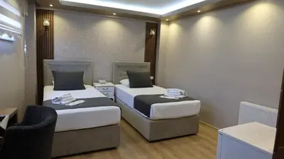 a room with two beds and a chair in it at ÜSKÜDAR OTEL in Istanbul
