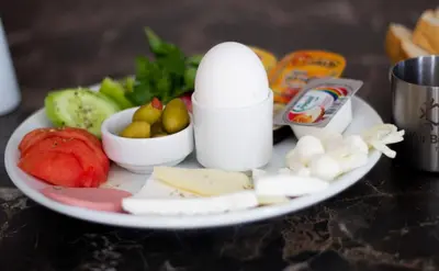 a plate of food with cheese and fruit on a table at KAR BEYAZ HOTEL BURSA in Bursa