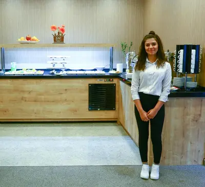 a woman standing in front of a counter in a kitchen at Burçman Hotel Vişne in Yıldırım
