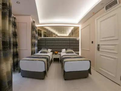 a room with three beds and a table at Crowned Hotel in Istanbul