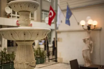 a stone fountain in front of a building with flags at Cesmeli Konak Hotel Silivri in Silivri