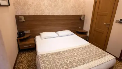 a bedroom with a bed and a wooden headboard at Cesmeli Konak Hotel Silivri in Silivri