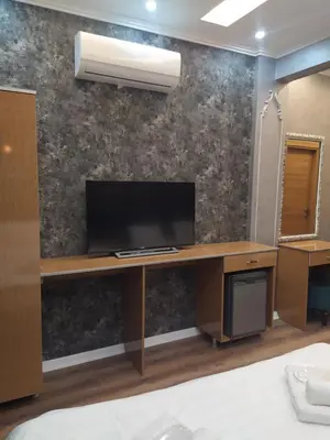 a bedroom with a desk with a television on a wall at BoNaMi Hotel in Istanbul