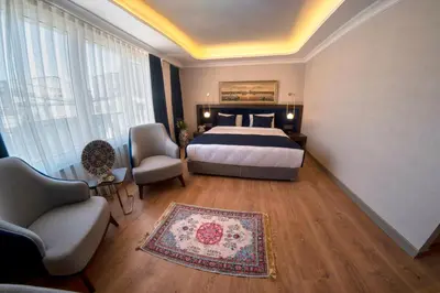 a bedroom with a bed and a couch and chairs at Nevi Hotel & Suites Istanbul Taksim in Istanbul