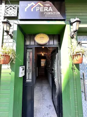 a entrance to a green building with potted plants at Pera Pansiyon in Bursa