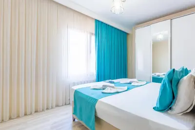 a bedroom with a bed with blue curtains and a window at MELİSA SUİT RESİDENCE in Istanbul