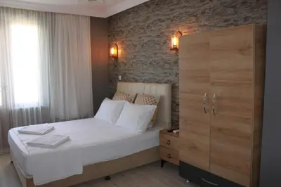 a bedroom with a white bed and a brick wall at yelken apart hotel in Tekirdag