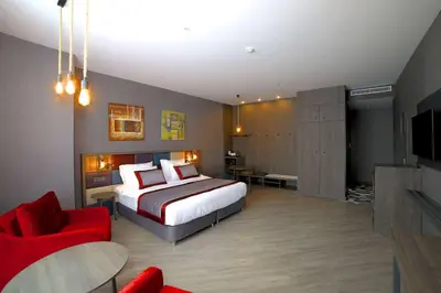 a hotel room with a bed and a red chair at Ramada Encore by Wyndham Istanbul Avcilar in Istanbul