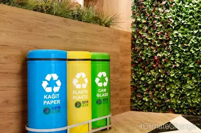 two green and yellow trash cans sitting next to a hedge at Ramada Encore by Wyndham Istanbul Avcilar in Istanbul