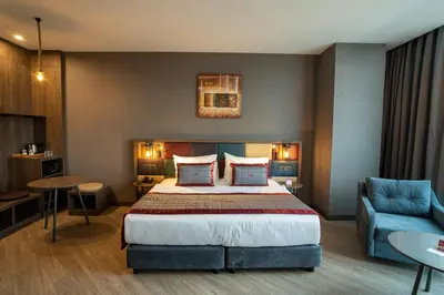 a hotel room with a bed and a blue couch at Ramada Encore by Wyndham Istanbul Avcilar in Istanbul