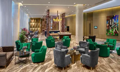 a lobby of a hotel with green chairs and tables at Wanda Vista Istanbul in Istanbul