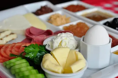 a tray of different types of cheese and vegetables at Hotel Yenibosna in Istanbul