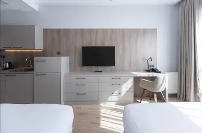 a white kitchen with a desk and a tv on the wall at Antwell Suites in Istanbul