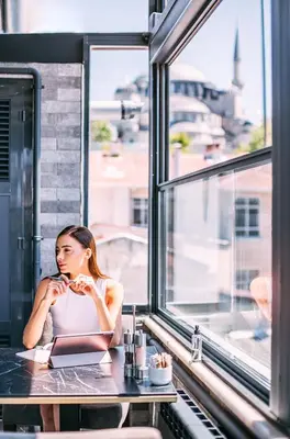 a woman sitting at a table looking out a window at RW BOUTIQUE HOTEL in Istanbul