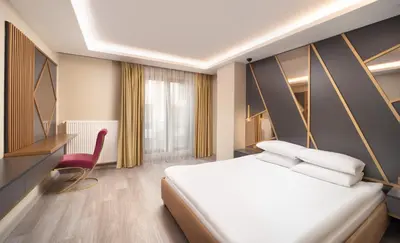 a hotel room with a bed and a red chair at Family Time Suites Hotel in Istanbul