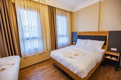 a bedroom with a bed with white sheets and windows at Grand Balyan Hotel & Restaurant in Istanbul