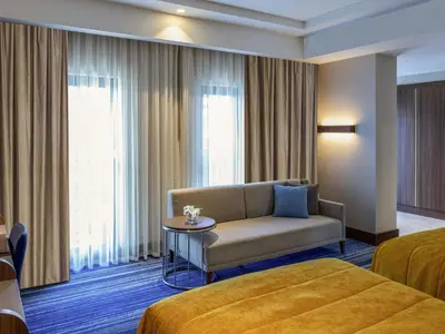 a hotel room with a couch and a window at Mövenpick Hotel Istanbul Asia Airport in Istanbul