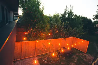 a backyard with a fence and a table with lights at Bahçeli Concept Sapanca in Sapanca