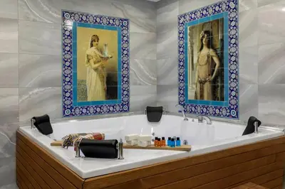 a bathroom with a tub with two pictures on the wall at LAGUN CASTLE HOTEL&SPA in Yalova