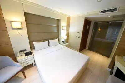 a bedroom with a large white bed and a chair at Hotel Le Mirage in Istanbul