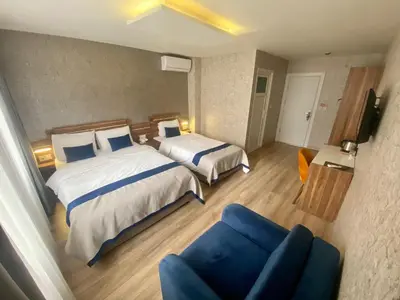 a hotel room with two beds and a blue couch at ERA PALACE HOTEL B BLOK in Istanbul